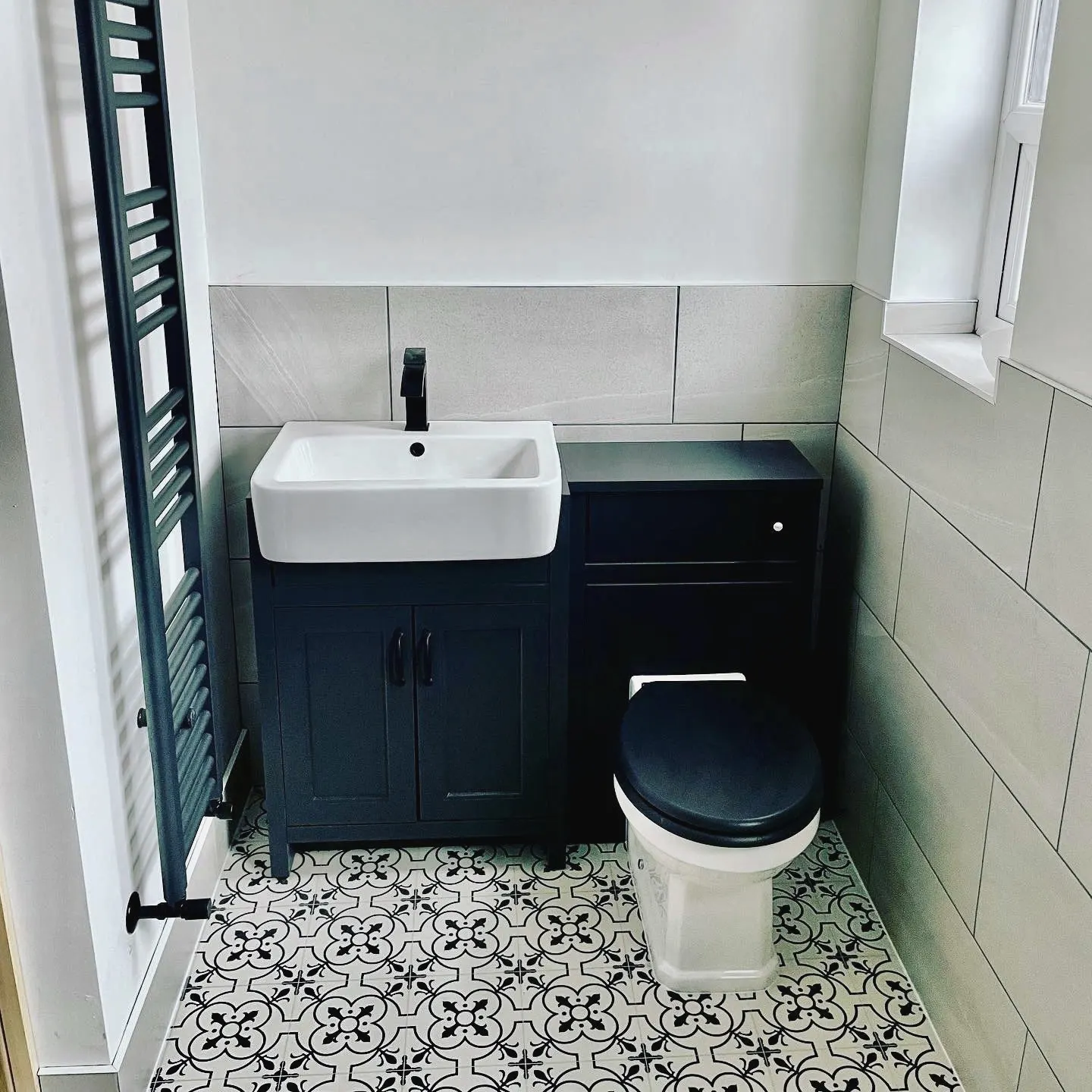 Fitted vanity unit and toilet in dark blue, on patterned floor tiles