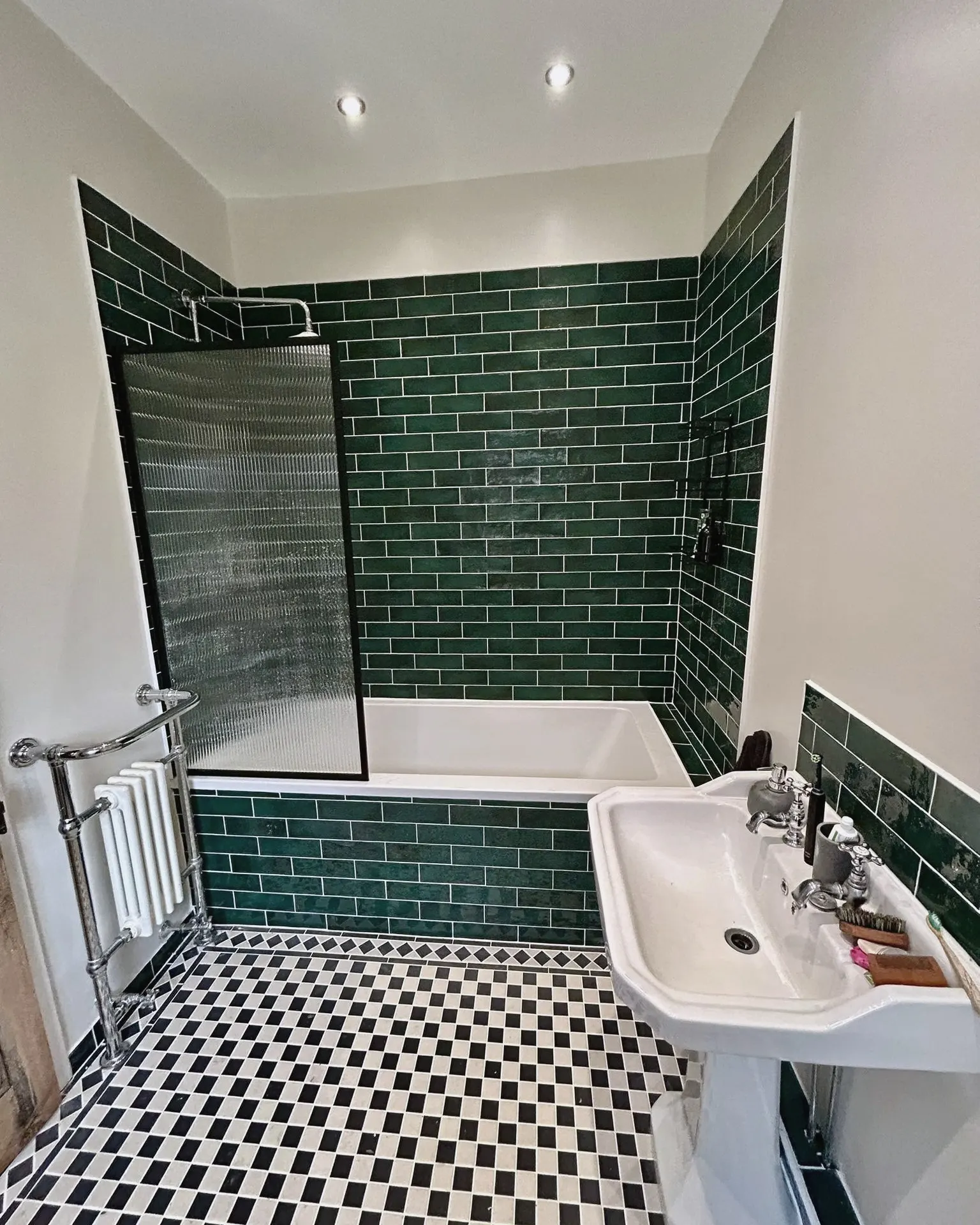 Bathroom with green metro wall tiles, a shower over the bath and a black and white chequered floor