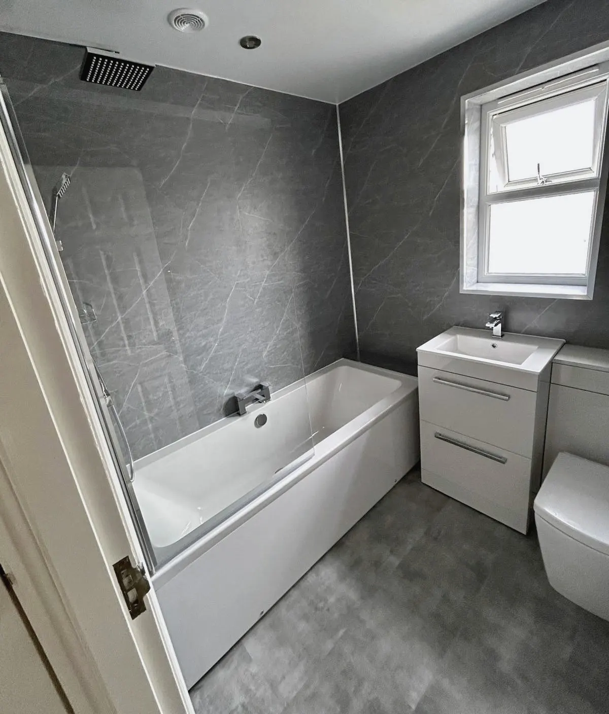 Bathroom with grey wall panels, a fitted bath and a white vanity unit