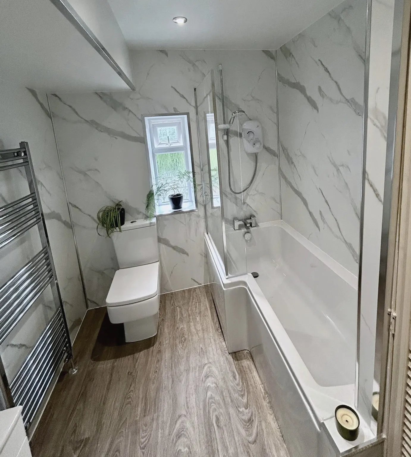 Shower bath between marble-effect walls, with a wood-effect floor